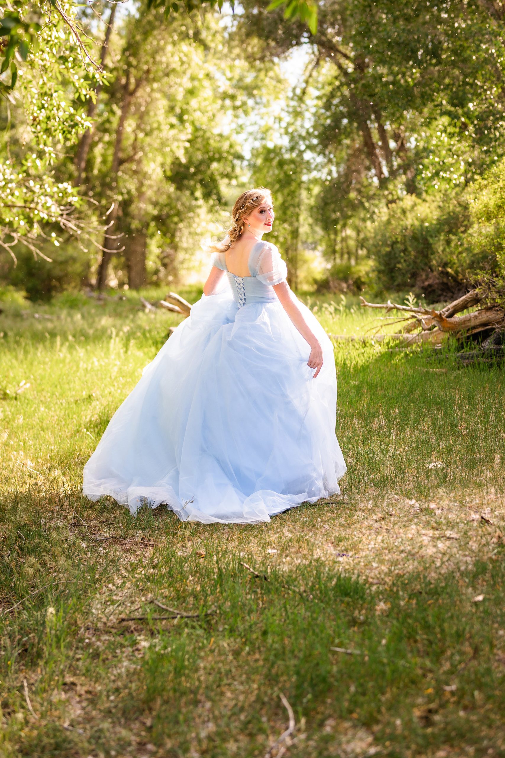 bride in blue dress in whimsical forest with dress. swooshing behind her