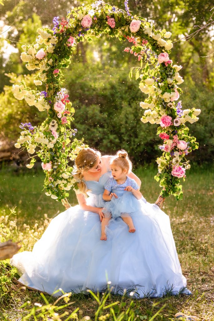 bride with daughter on swing covered in bright colored spring flowers