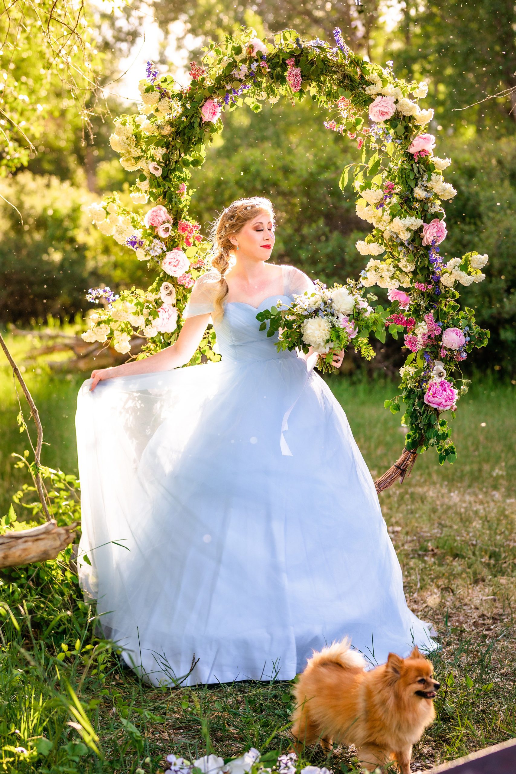 bride in blue dress standing in front of flower swing