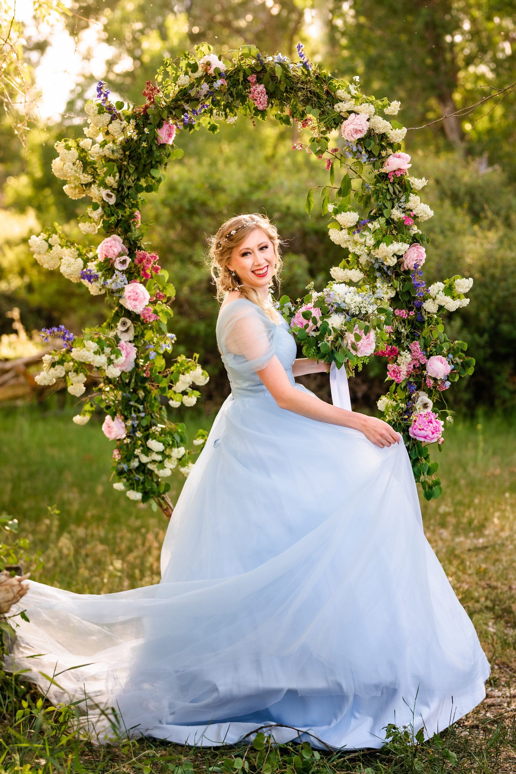 bride happy while in blue dress with swing covered in flowers