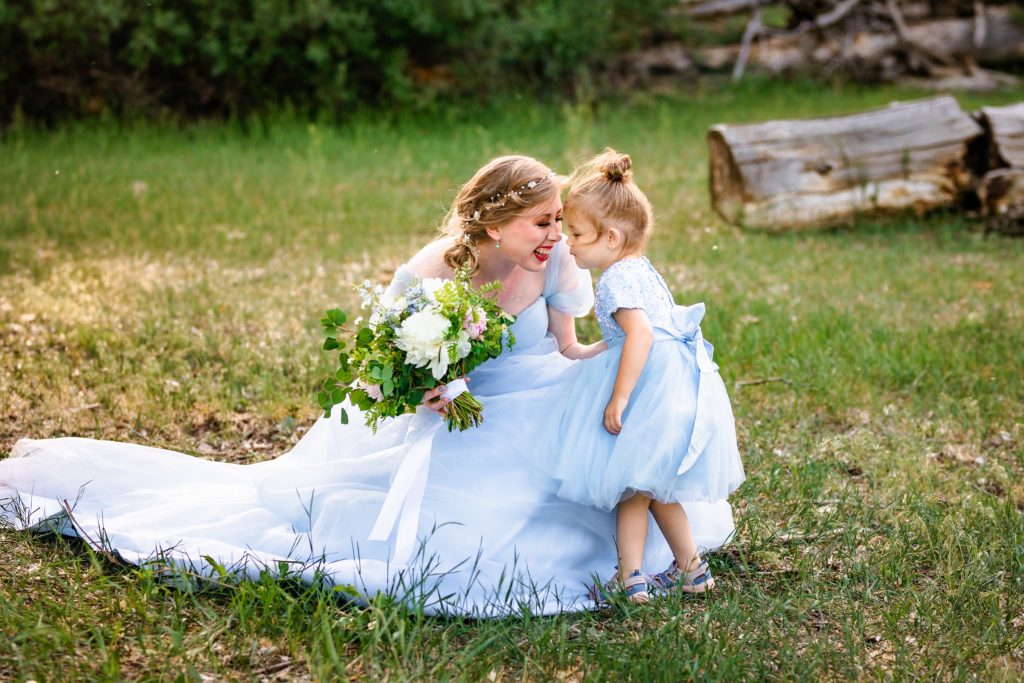 bride in blue dress snuggles noses with toddler daughter in blue dress