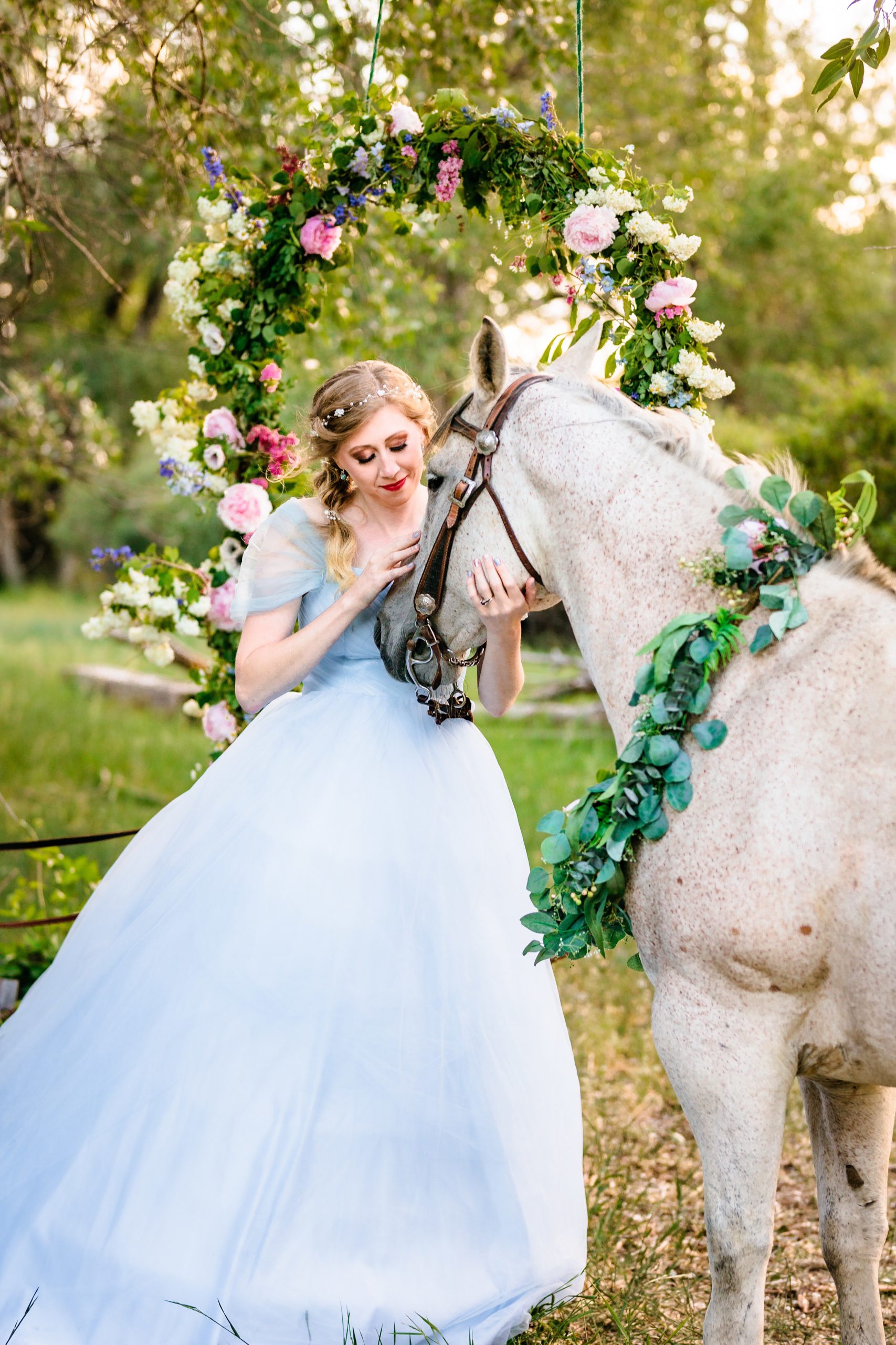 beautiful bride in blue dress speaks to white horse