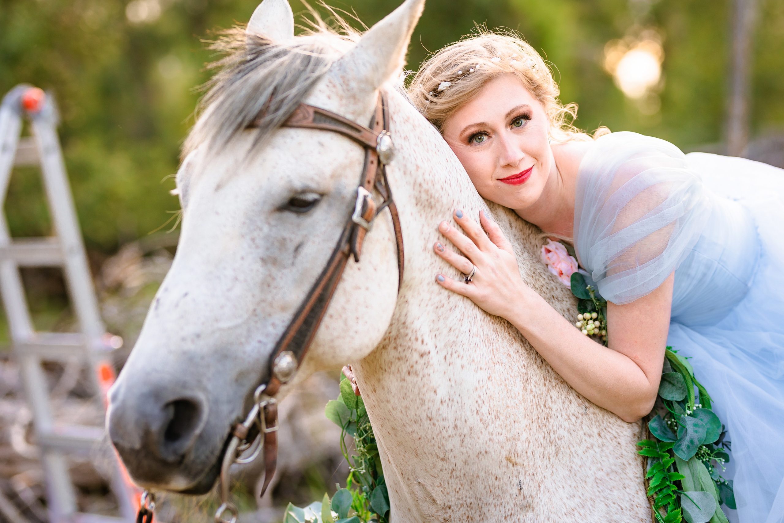 bride in blue dress lays on horse's mane