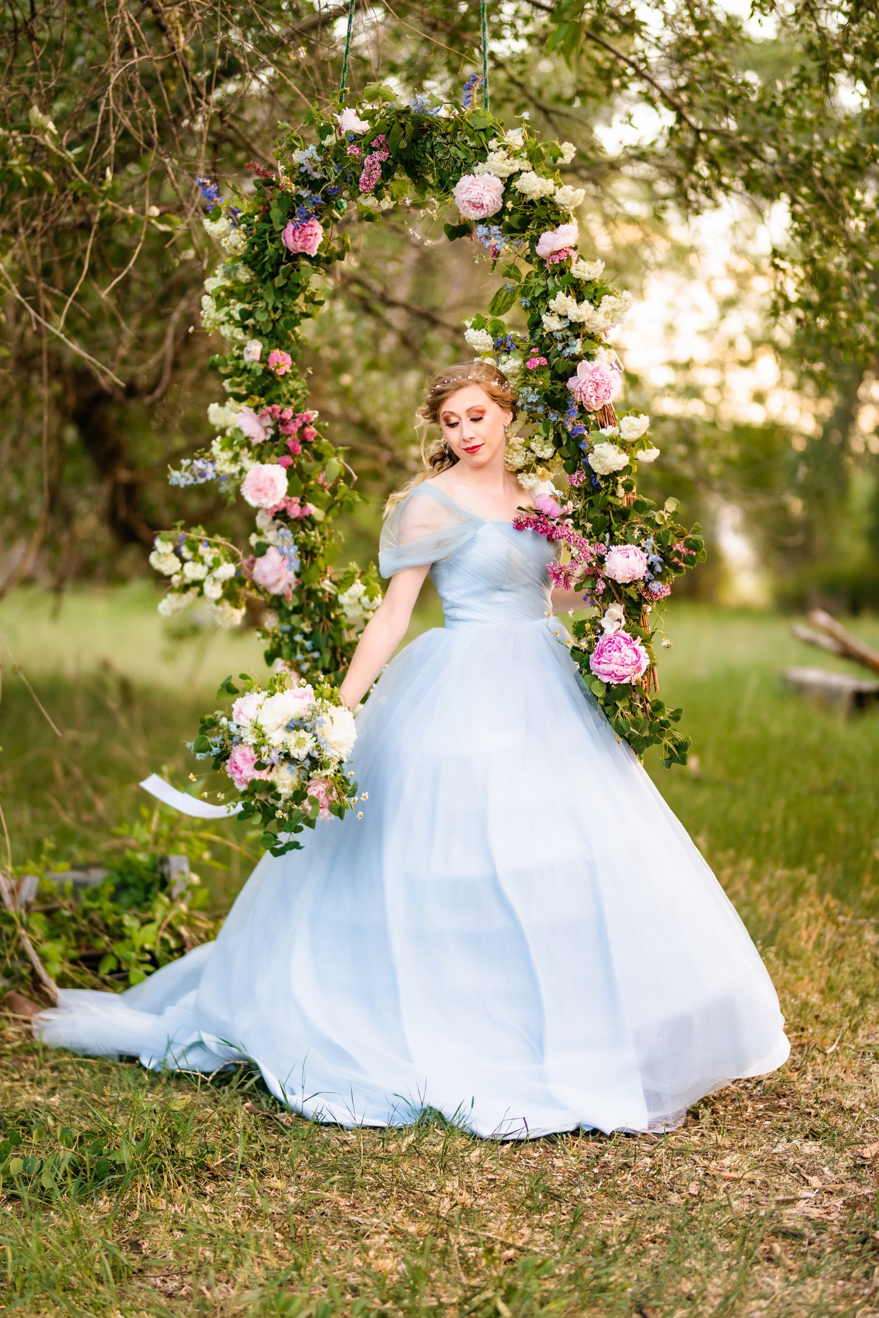 bride in blue dress swinging on flower swing in Jackson Hole, WY