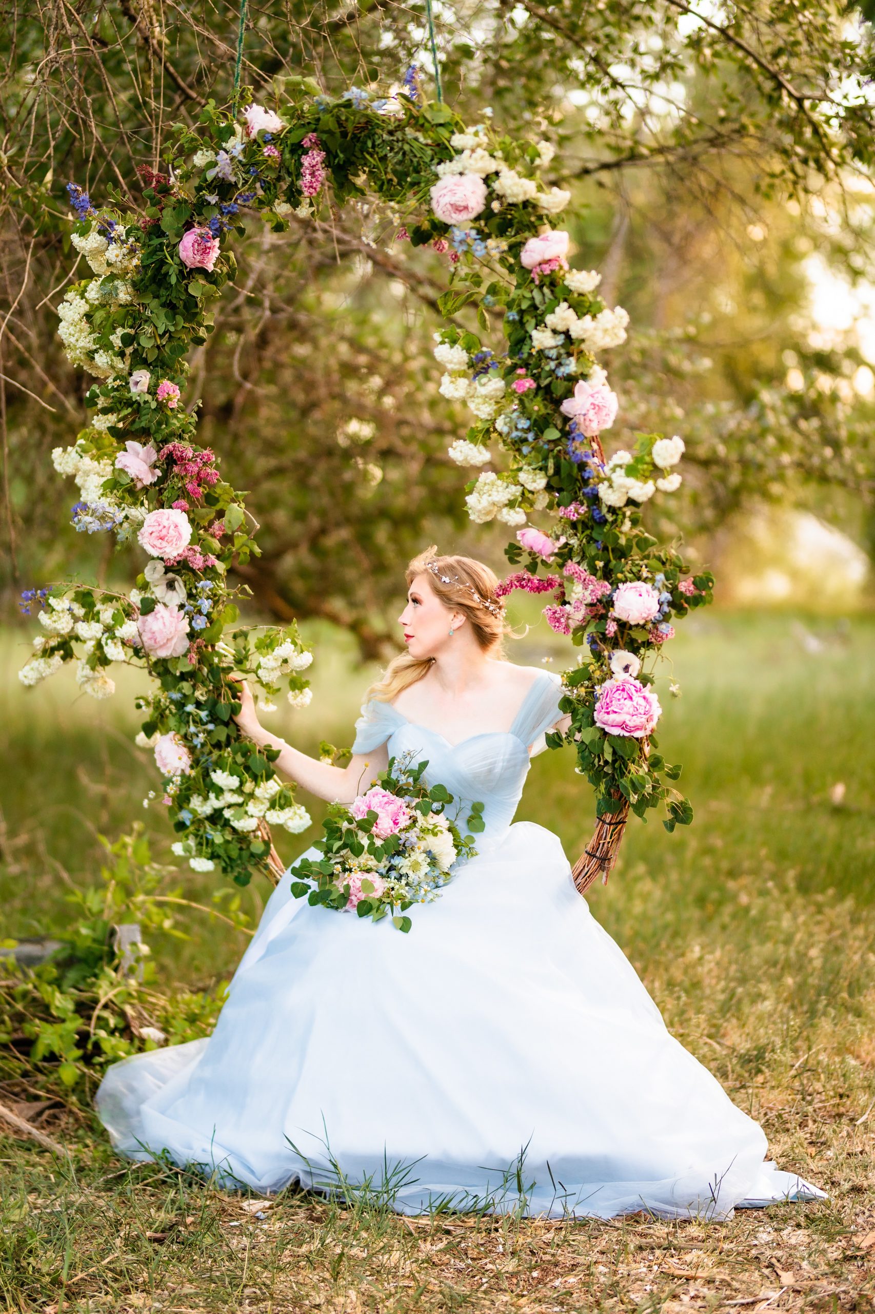 bride in blue dress showcases flower swing in Jackson Hole