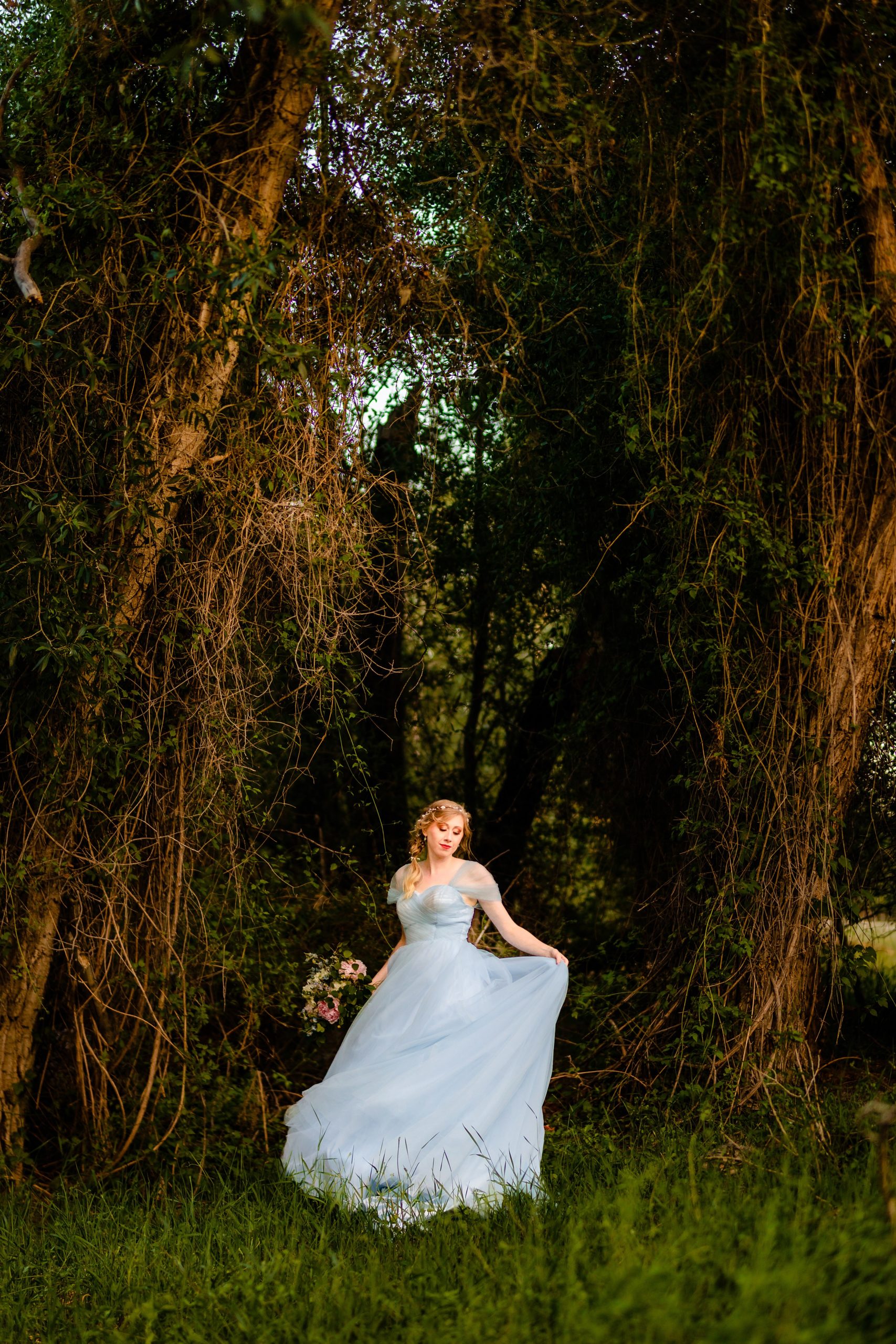bride in blue dress standing alone in dark forest