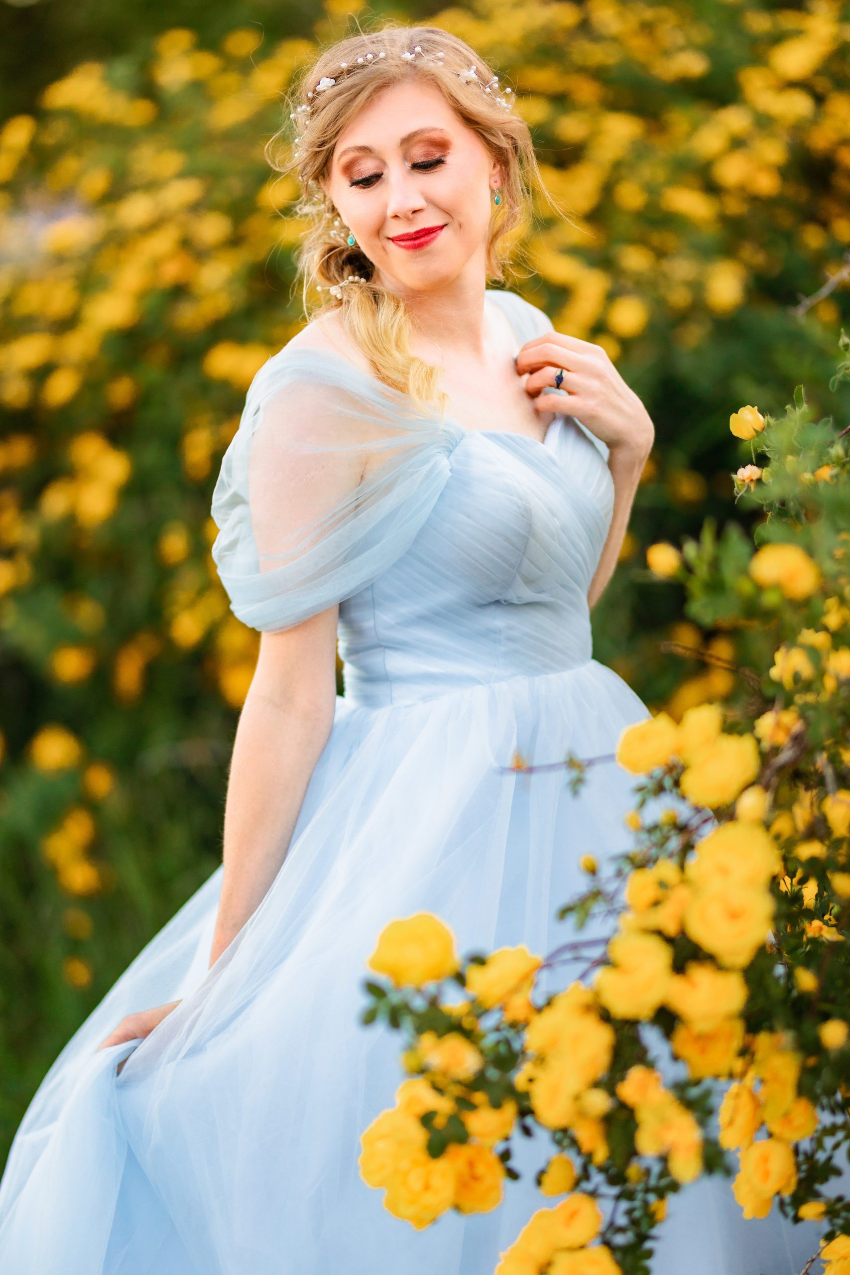 bride in blue dress in rosebush with yellow roses
