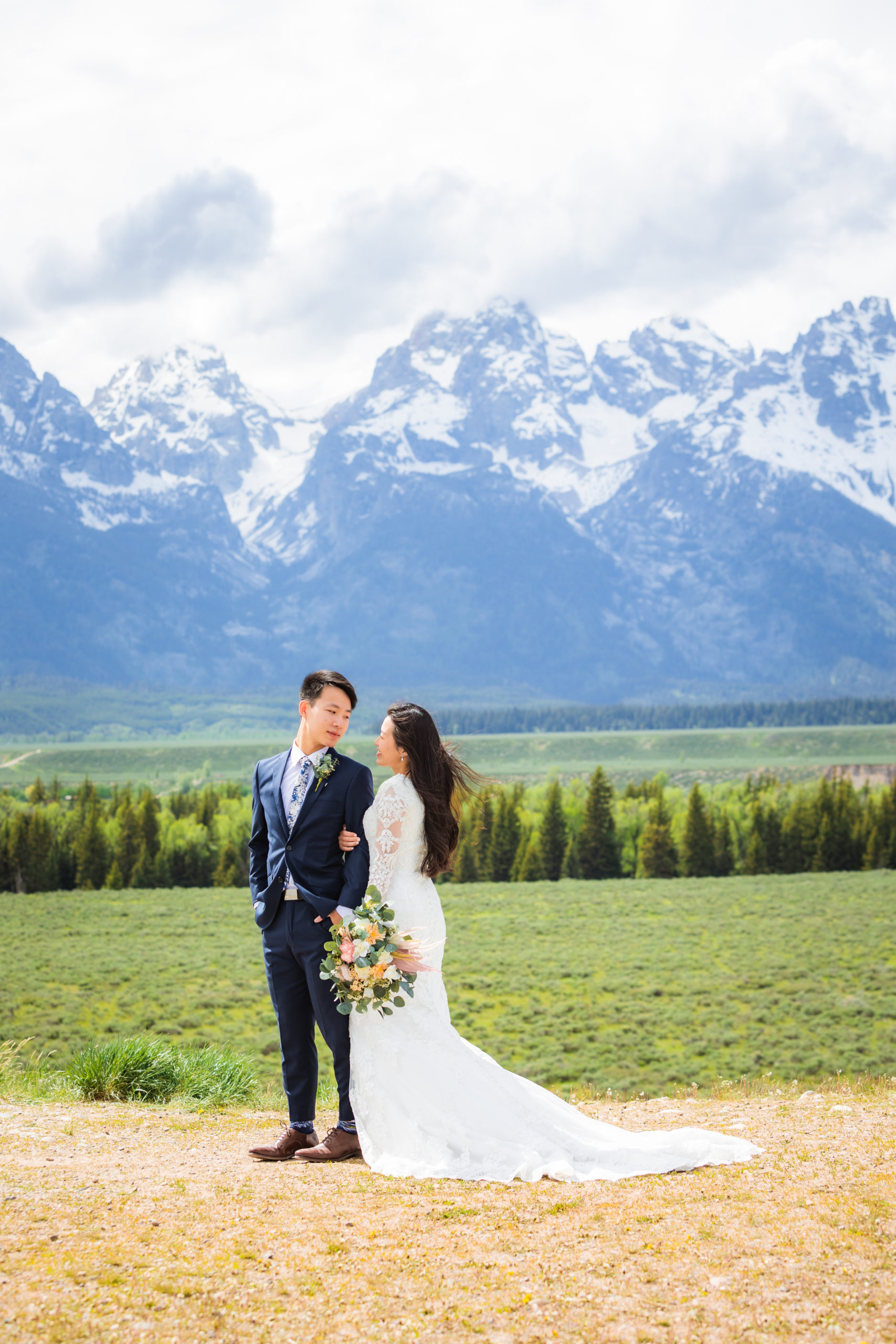 bride holding groom's arm at mountain view turnout at grand teton national park