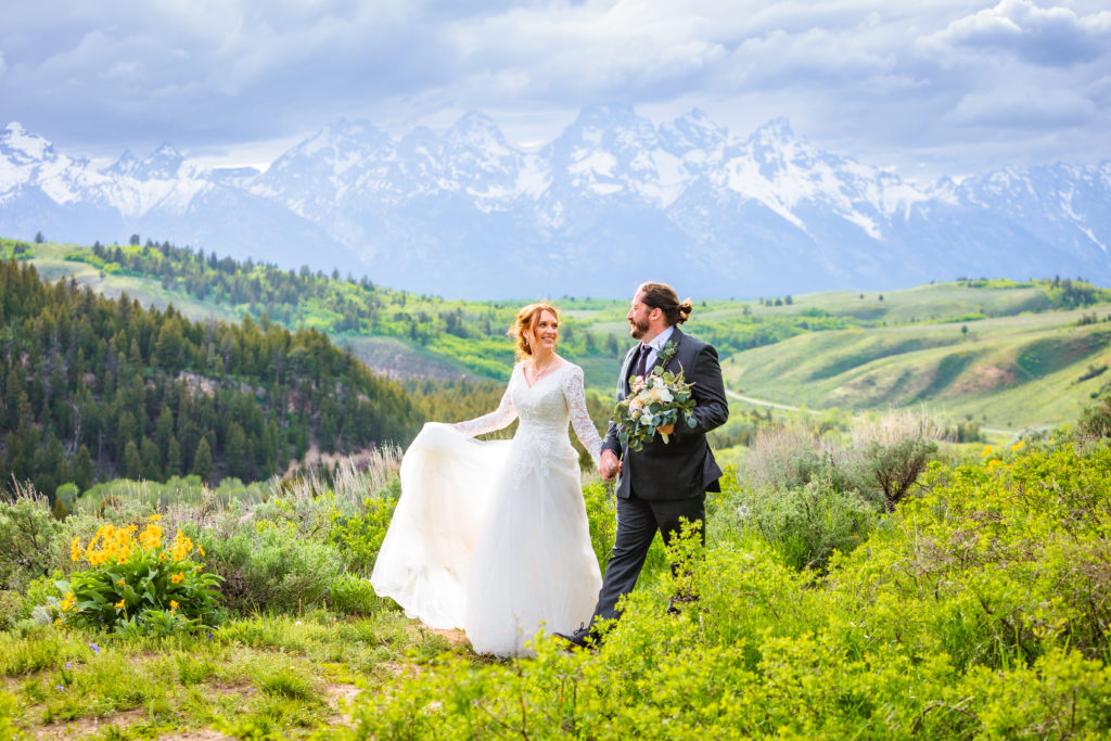 whimsical bride and groom walking next to the tetons in grand teton national park wedding