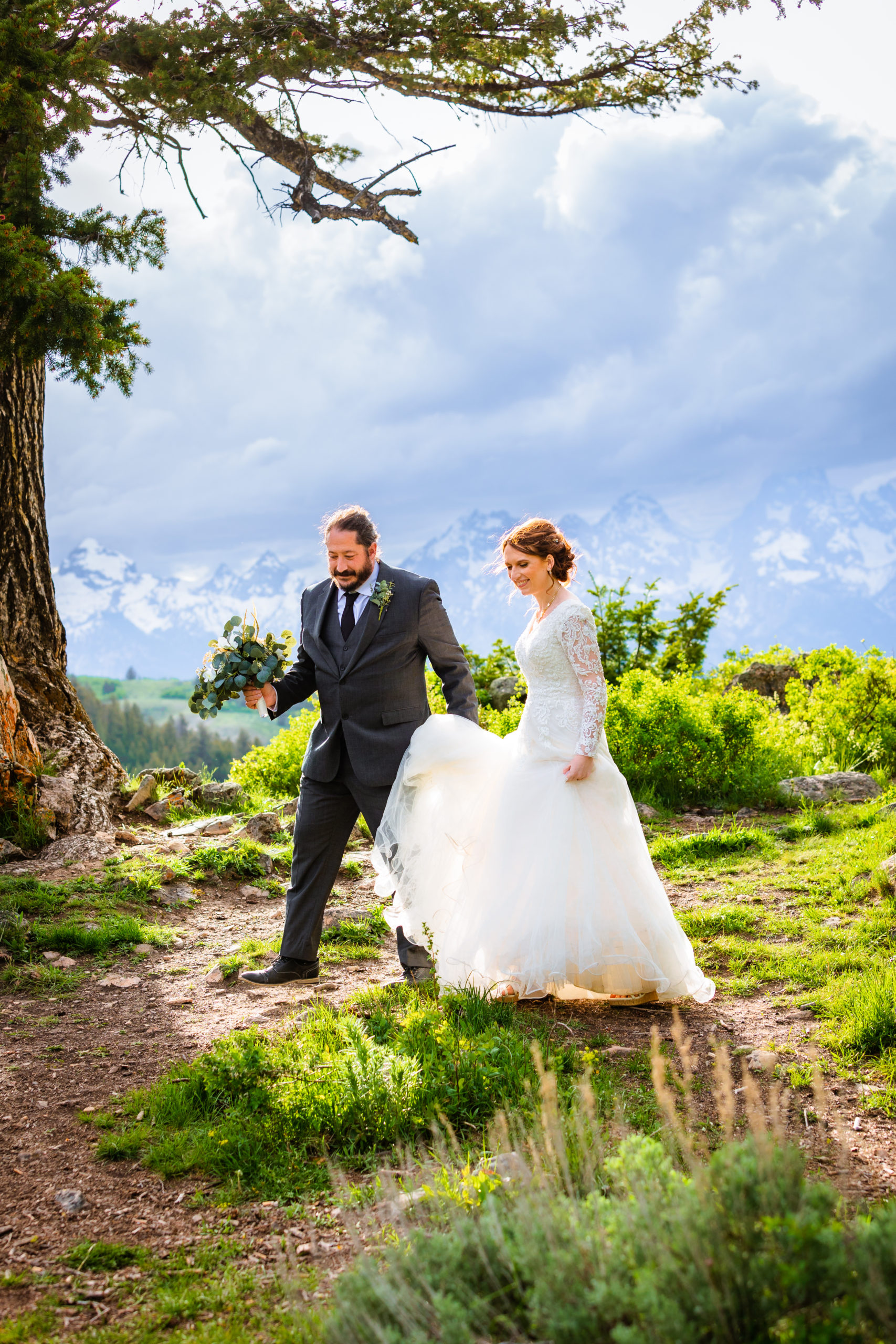 bride and groom walking away from tetons holding hands
