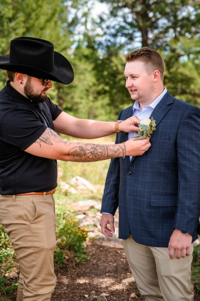 Jackson Hole wedding photographers capture groom getting boutonniere put on before Windy Wedding Tree Elopement ceremony