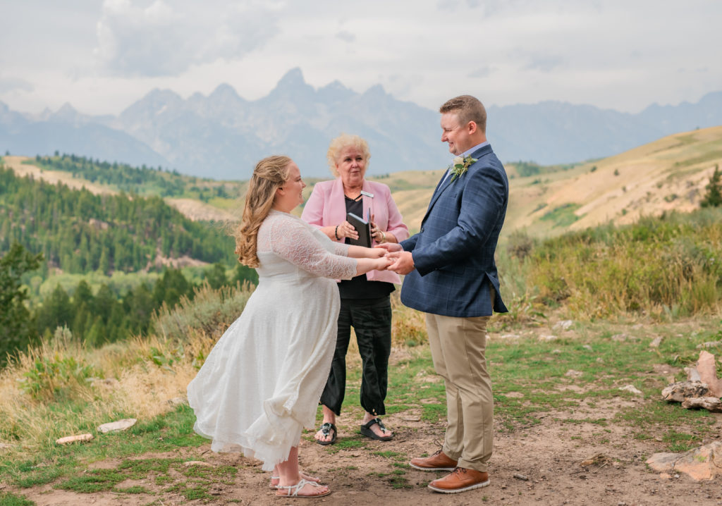 Jackson Hole wedding photographer captures bride and groom holding hands during ceremony