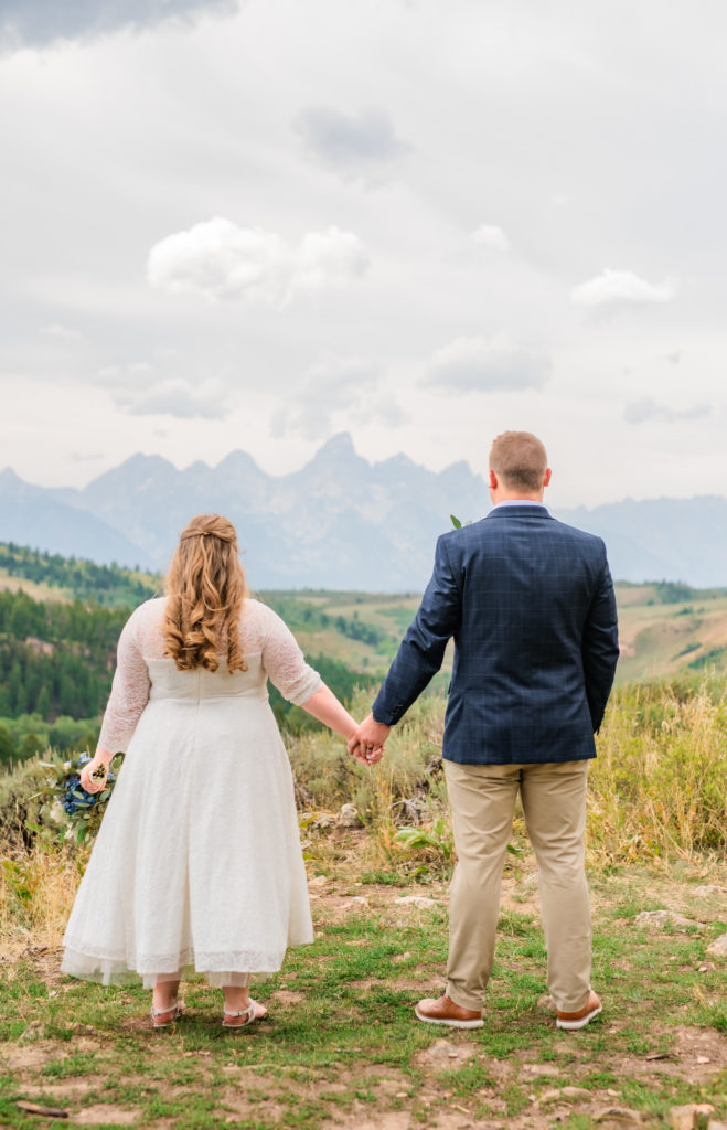Jackson Hole wedding photographer captures bride and groom holding hands and looking off into the distance