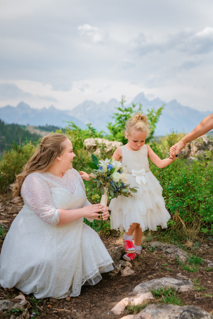Jackson Hole wedding photographer captures bride and flower girl having fun outdoors