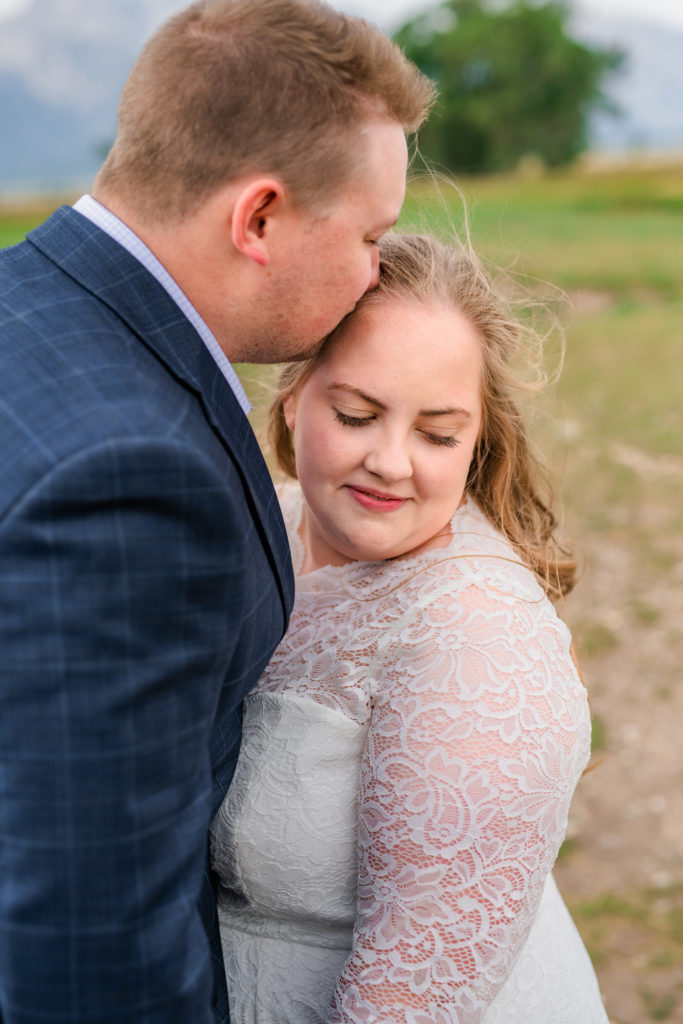 groom kissing bride's forehead during jackson hole wedding portraits