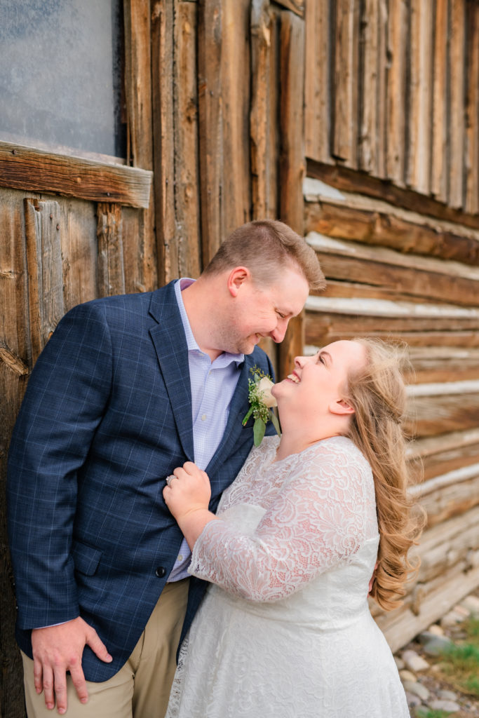 Jackson Hole wedding photographers capture groom wearing navy sports coat and bride wearing long sleeve bridal gown during portraits