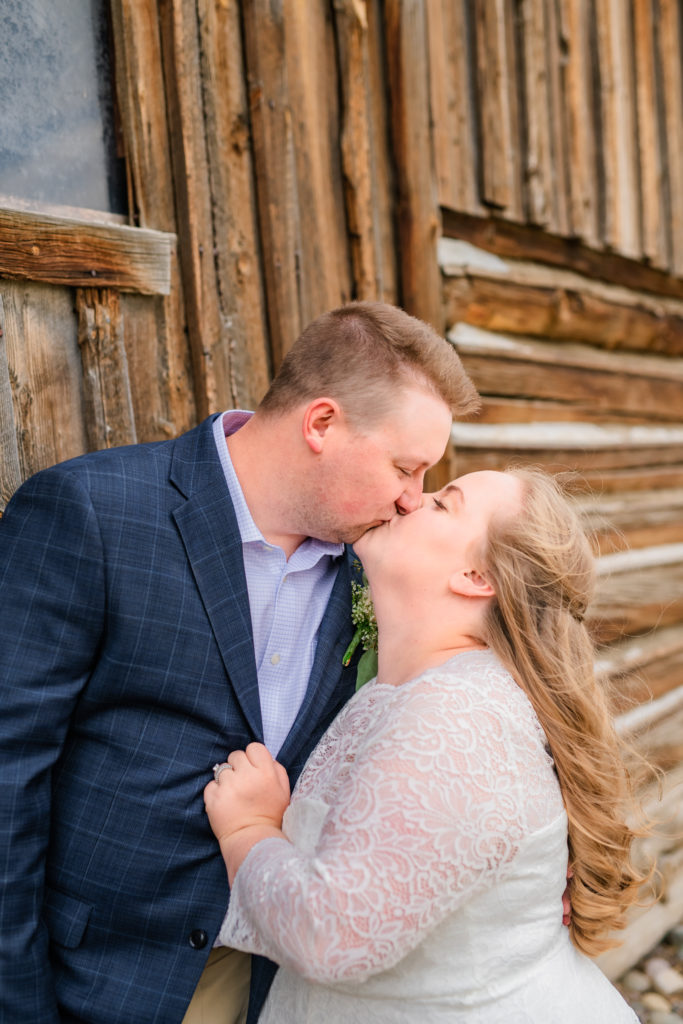 Jackson Hole wedding photographers capture bride pulling on grooms jacket and kissing him