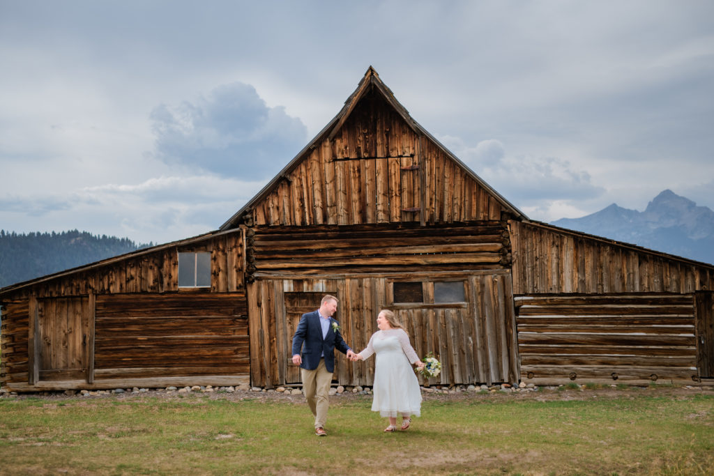 Jackson Hole wedding photographer captures newly married couple walking and holding hands in Jackson Hole wedding portraits