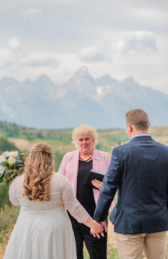 Jackson Hole wedding photographer captures bride and groom holding hands during Windy Wedding Tree Elopement ceremony