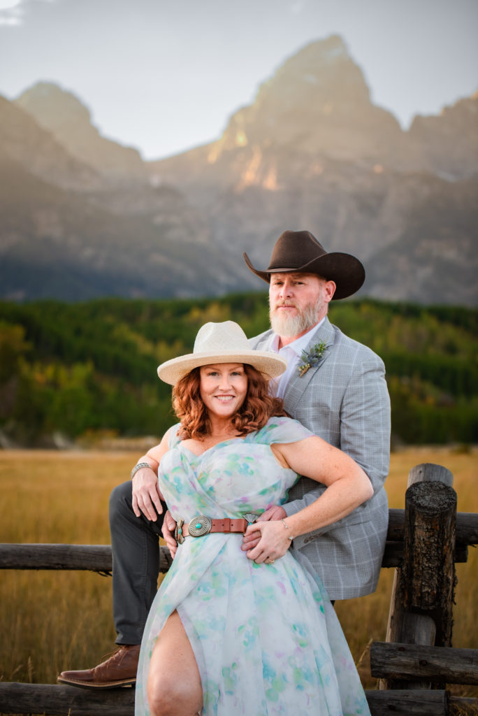 Jackson Hole wedding photographer captures bride and groom leaning against fence in Grand Teton National Park wedding
