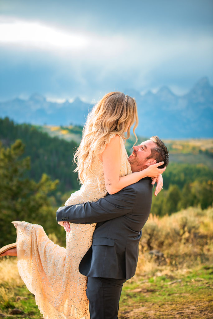 Jackson Hole wedding photographer captures groom lifting bride during outdoor engagements