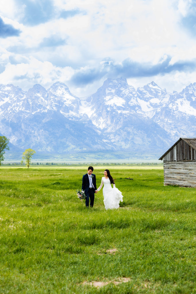 Jackson Hole wedding photographer captures bride and groom walking through grand teton national park wedding