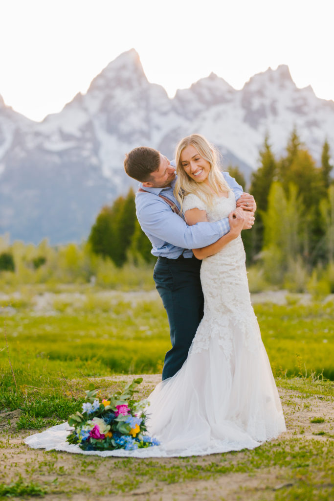 Jackson Hole wedding photographer captures groom hugging bride from behind in Grand Teton National Park