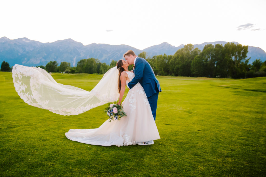 Jackson Hole wedding photographer captures bride and groom kissing with veil in the wind at classy jackson hole wedding venues