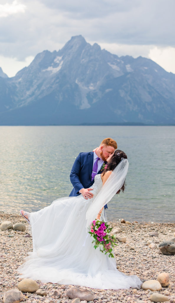 Jackson hole wedding photographer captures groom kissing bride in grand Teton national Park