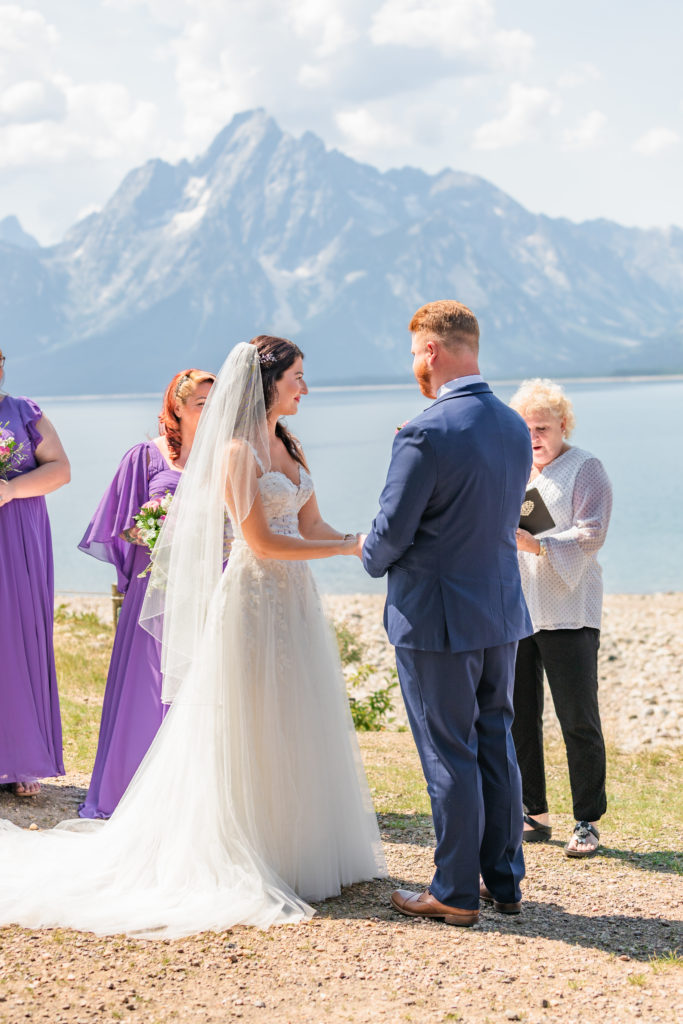 Jackson hole elopement photographer captures bride and groom holding hands and saying vows