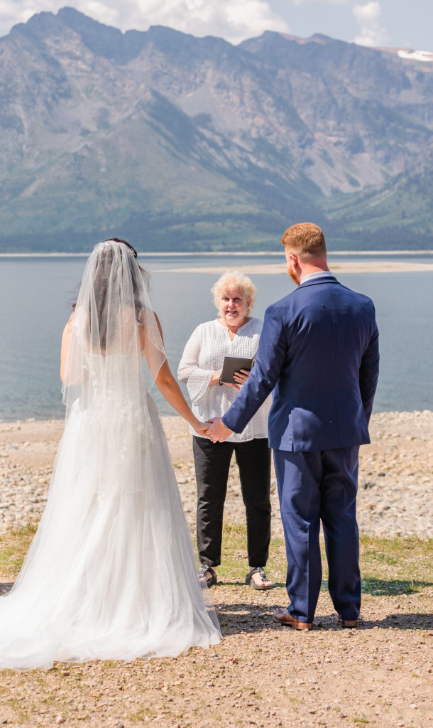 Jackson hole elopement photographer captures bride and groom holding hands during elopement ceremony
