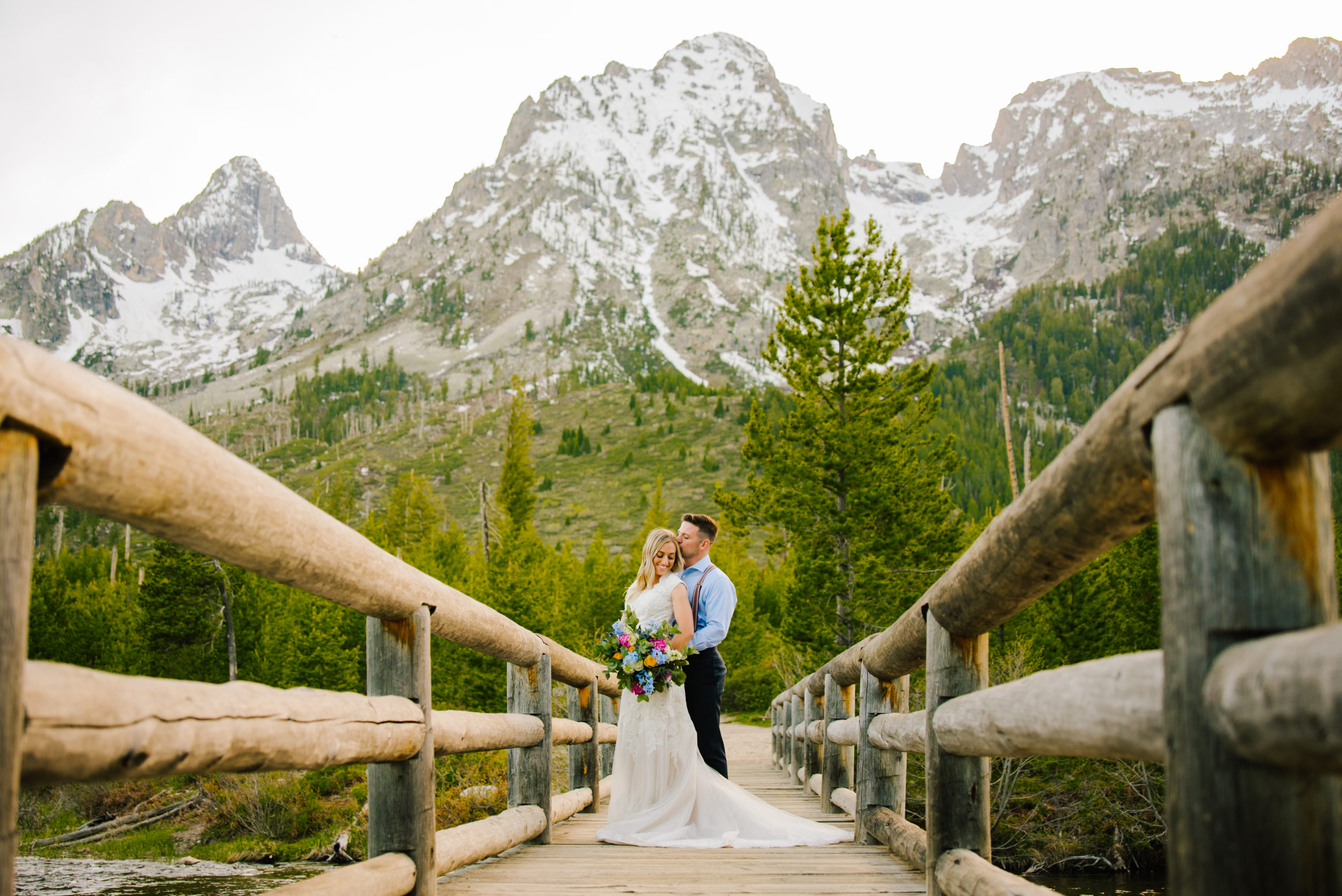 Jackson Hole wedding photographer captures bride and groom embracing on bridge in Grand Teton National Park