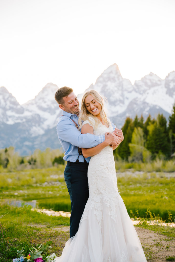 Jackson Hole wedding photographer captures newly married couple hugging and laughing