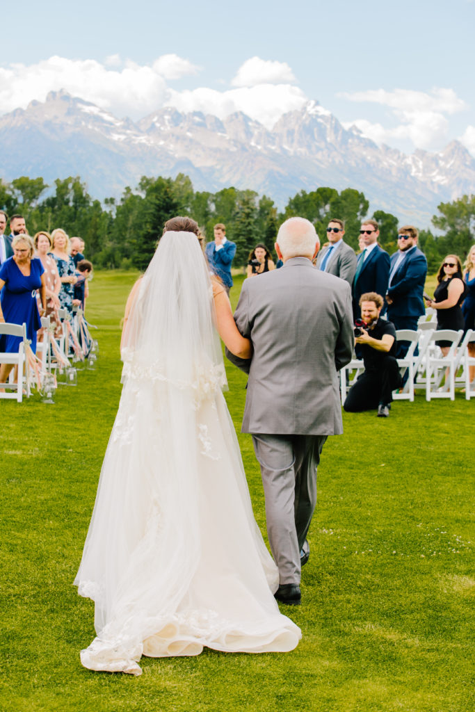 Jackson Hole wedding photographer captures bride being walked down aisle by her father at classy jackson hole wedding venues