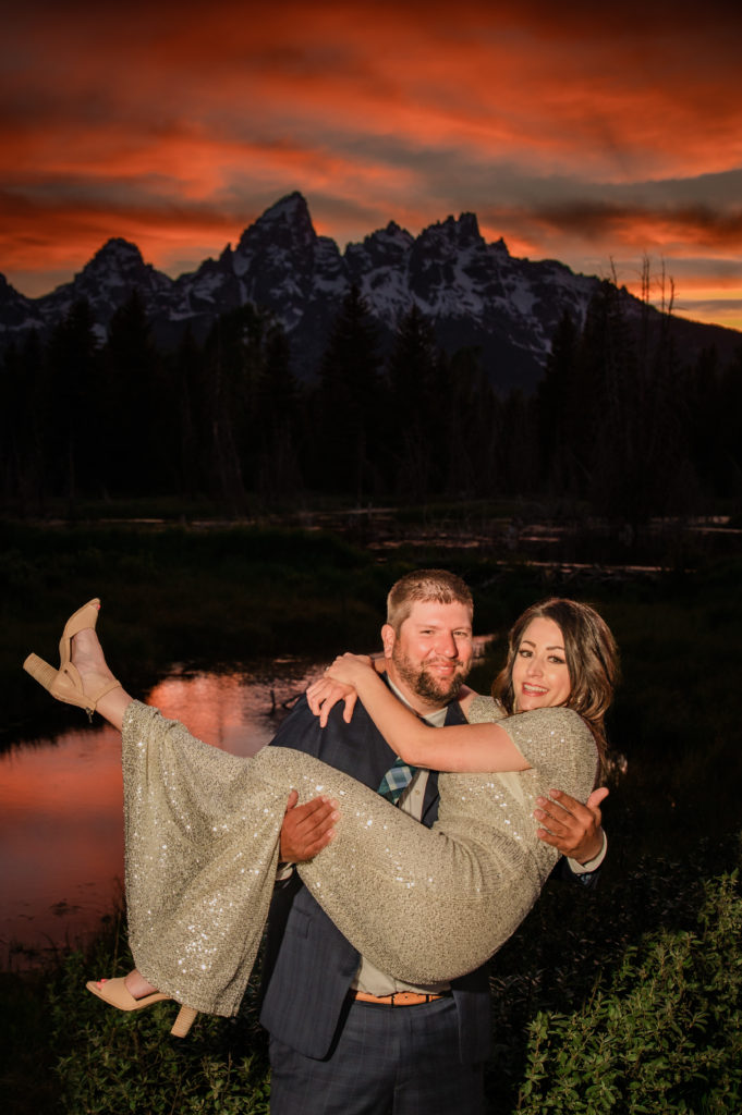 Jackson Hole elopement photographer captures groom lifting bride and holding her at sunset