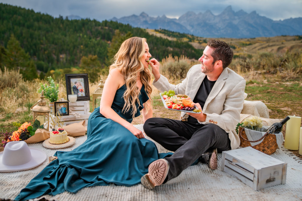 Jackson Hole wedding photographer captures bride and groom sitting on blanket eating lunch after grand teton elopement