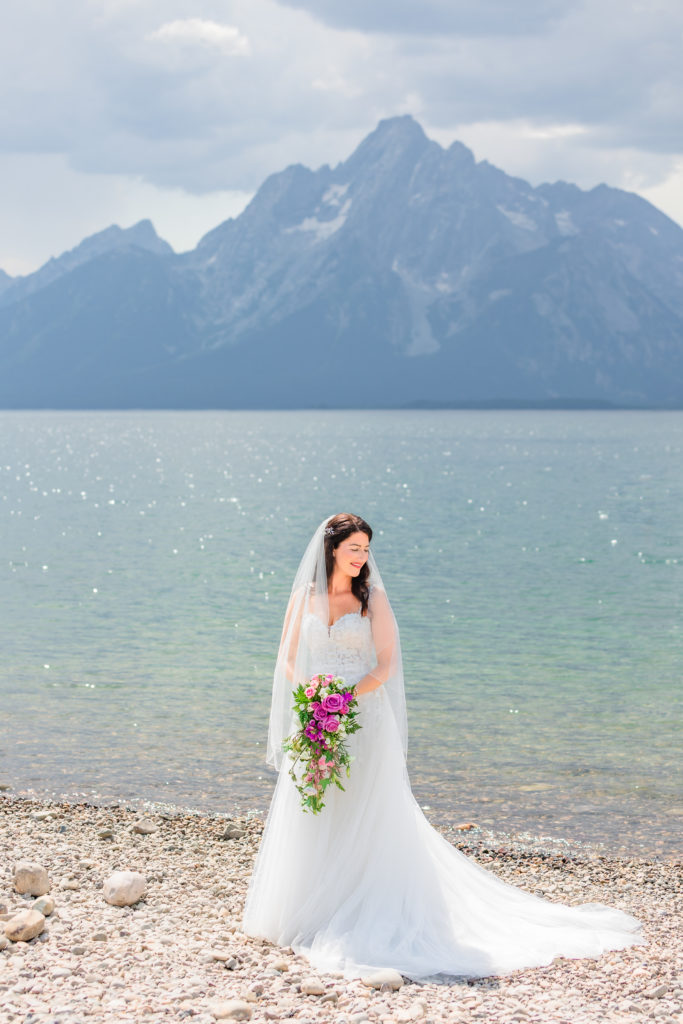 Jackson Hole wedding photographer captures bride holding bouquet standing in front of Colter Bay