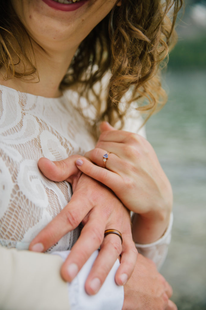 Jackson Hole wedding photographer captures groom hugging bride and close up of wedding rings
