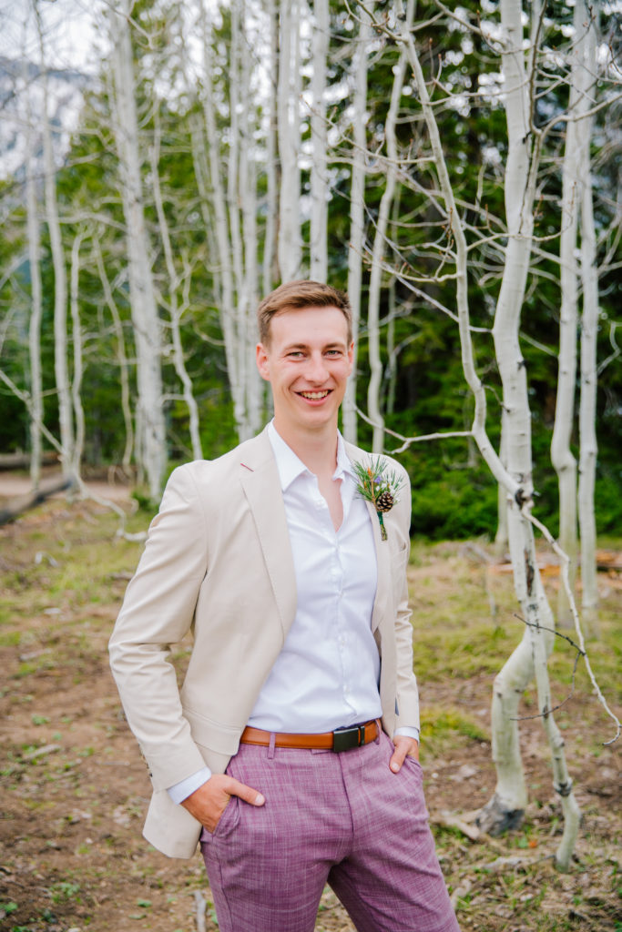 Jackson Hole elopement photographer captures groom wearing pink pants and cream coat during portraits
