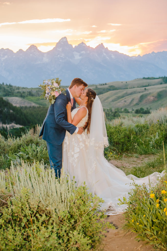 Jackson Hole wedding photographer captures bride and groom kissing during sunset bridal portraits