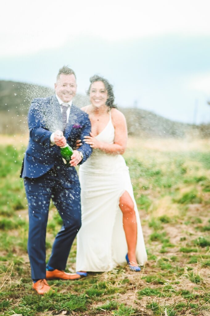 Jackson Hole wedding photographers capture couple celebrating with champagne pop