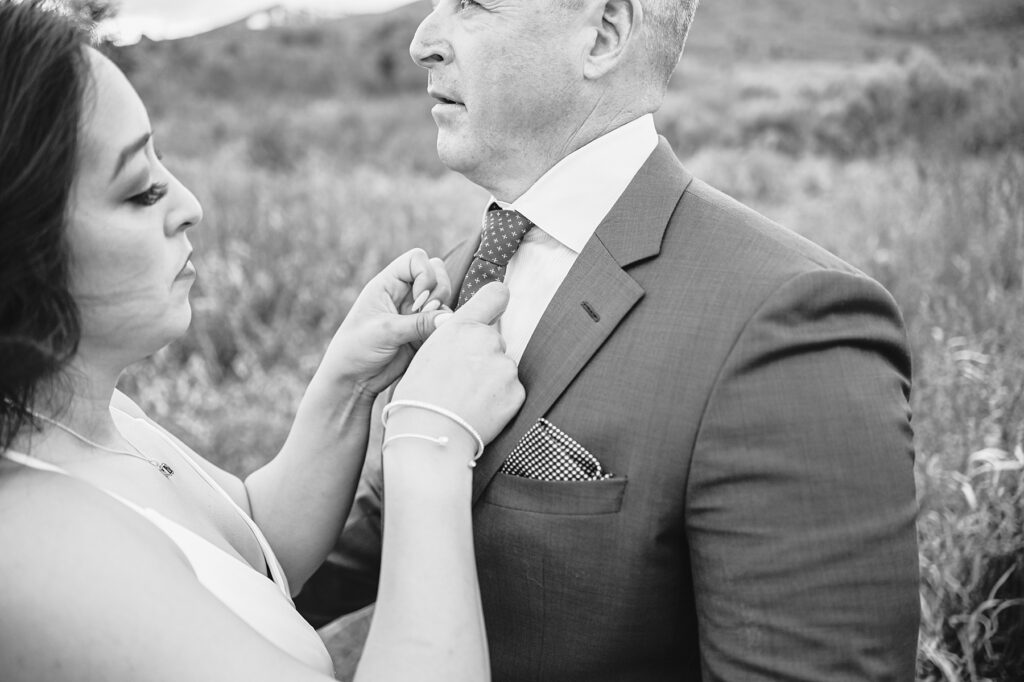 Jackson Hole wedding photographers capture bride adjusting groom's tie before elopement