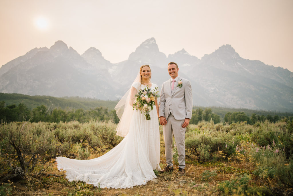 Jackson Hole wedding photographer captures bride and groom standing hand in hand after Grand Teton wedding with Jackson Hole videographer