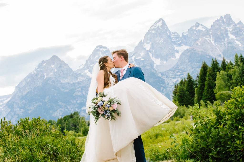 Jackson Hole wedding photographer captures groom holding bride and kissing her 