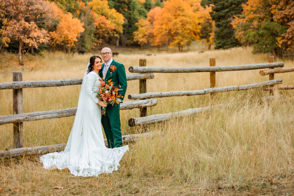 Jackson Hole elopement photographer captures couple embracing with groom wearing green suit and bride wearing wedding gown at micro grand teton wedding