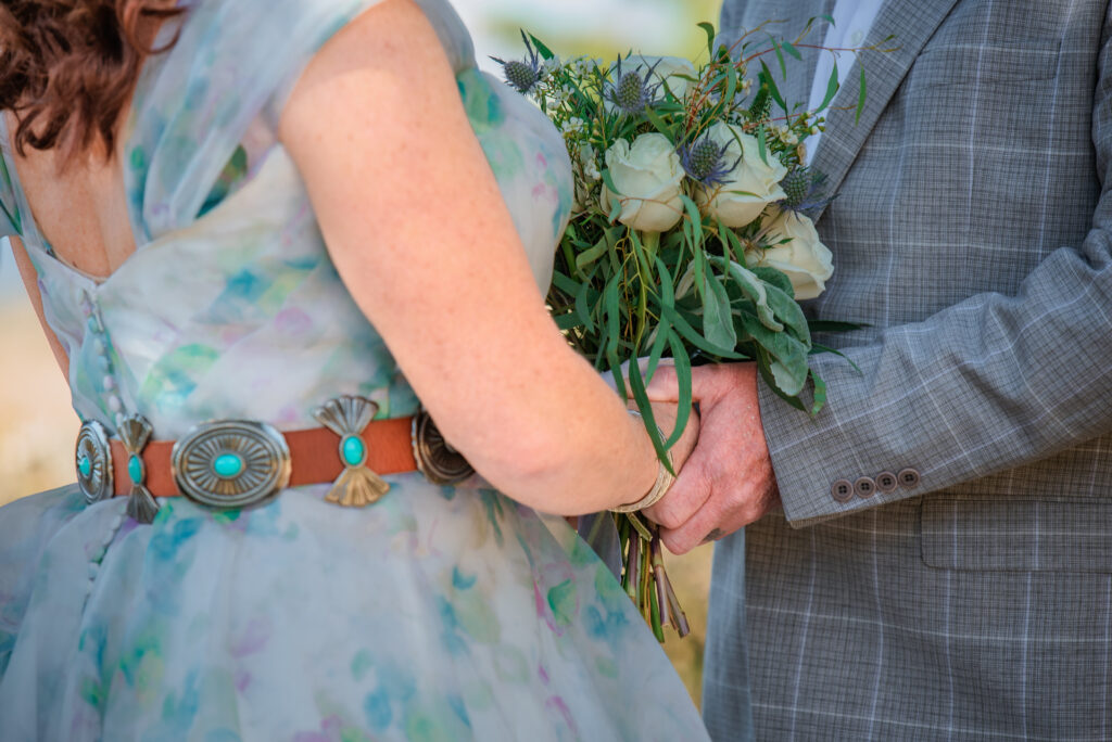 Jackson Hole photographers capture close up of bride and groom holding hands during ceremony