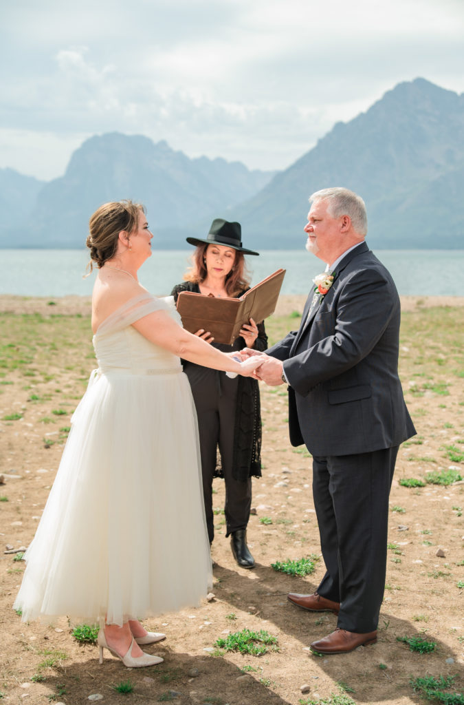 Grand Teton wedding photographer captures couple holding hands during ceremony
