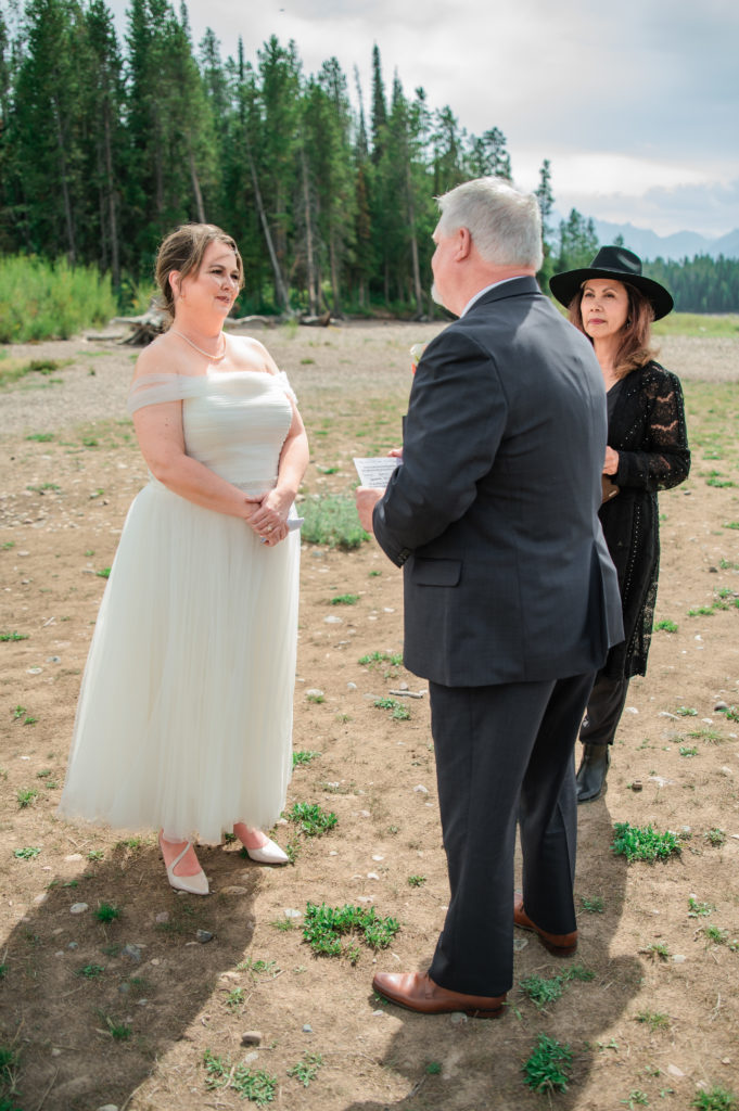 Jackson Hole elopement photographer captures bride looking at groom while groom reads vows
