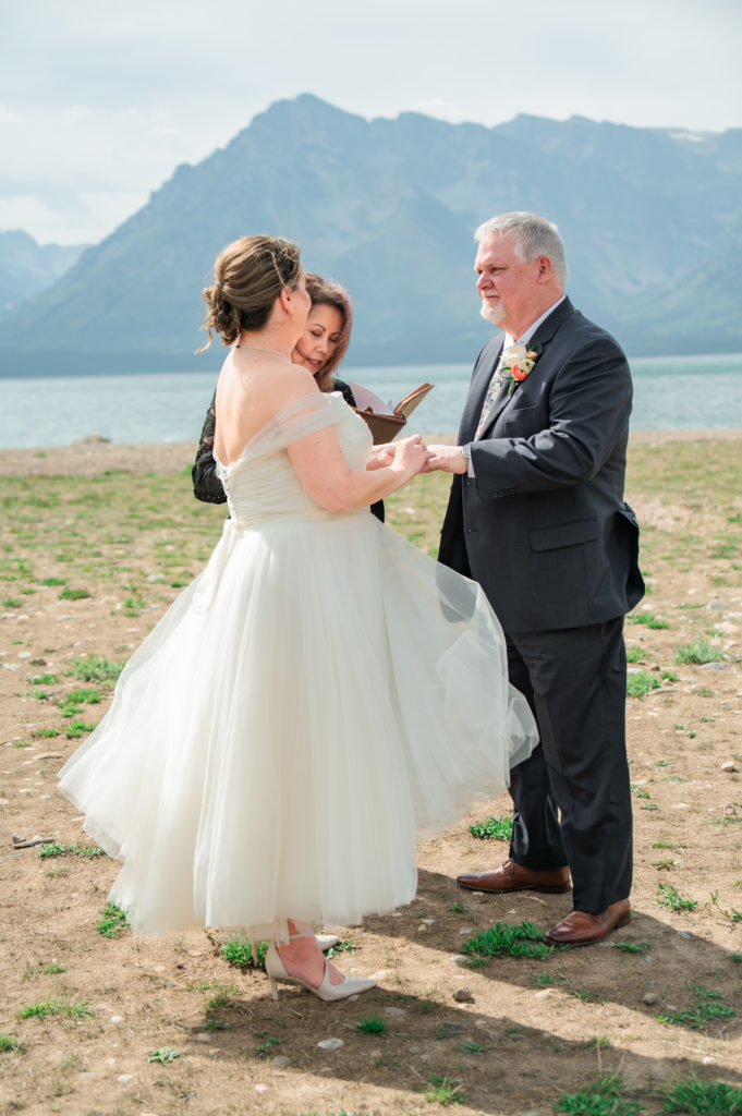 Jackson Hole photographer captures couple placing wedding rings on finger during grand teton wedding