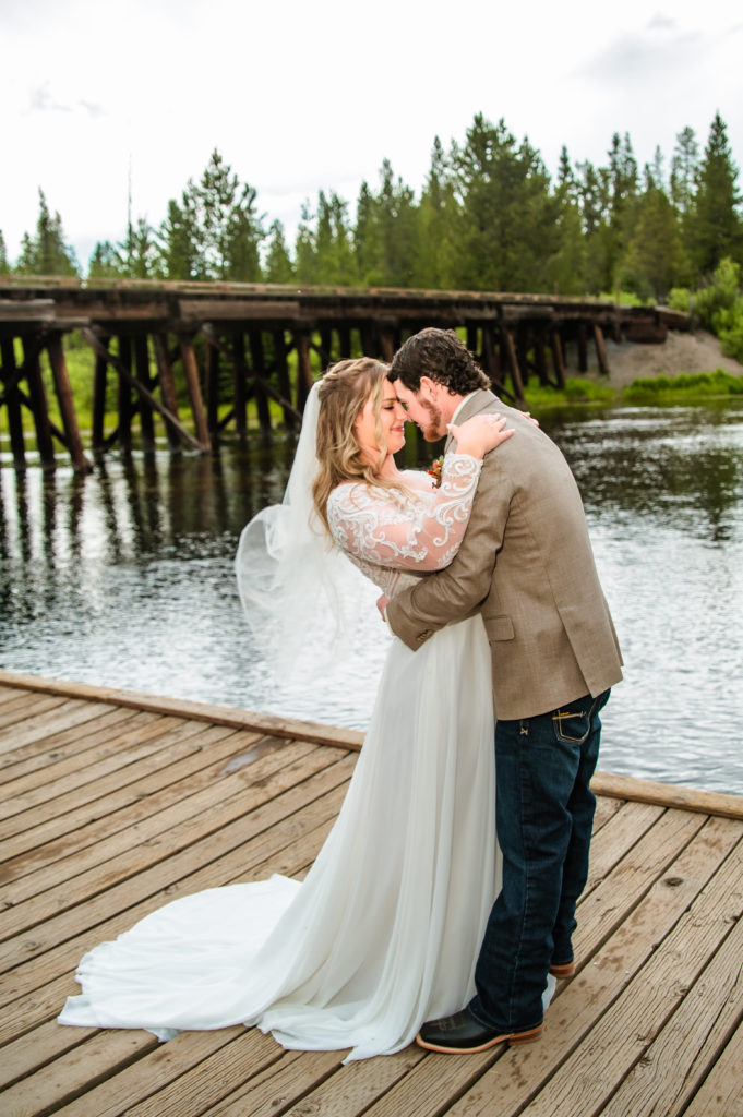 Jackson Hole wedding photographers capture newly married couple kissing on dock  after Jackson Hole wedding